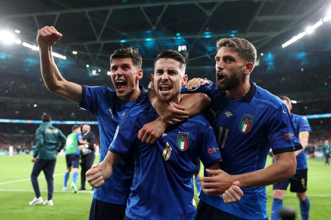 Jorginho celebrates with Matteo Pessina and Domenico Berardi after scoring Italy's winning penalty.