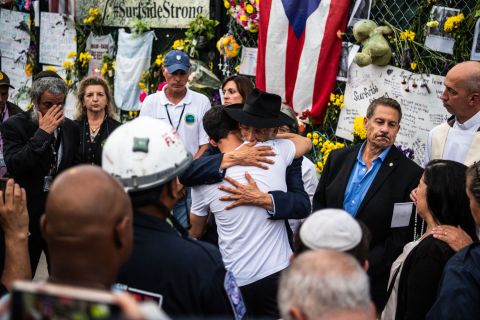 A member of Miami-Dade Fire Rescue hugs victims' family members and friends at the memorial near the collapsed building.
