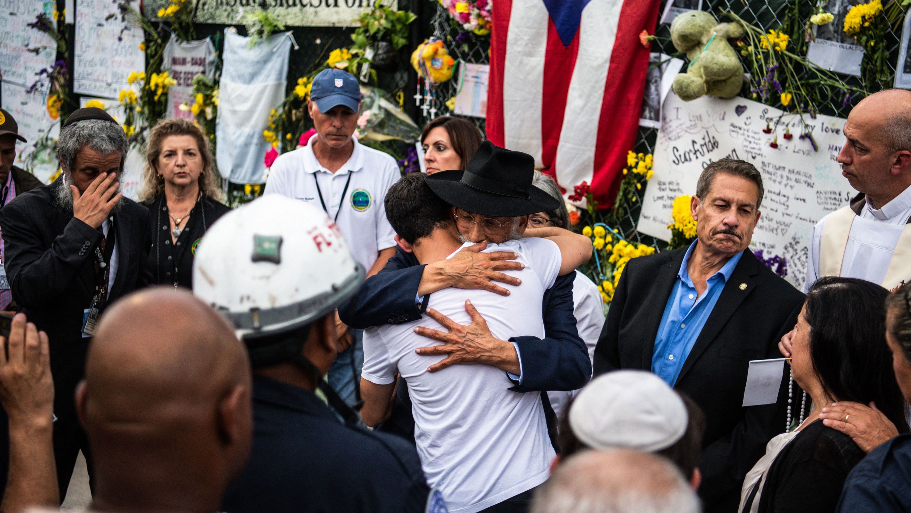 A member of Miami-Dade Fire Rescue hugs victims' family members and friends at the memorial near the collapsed building.