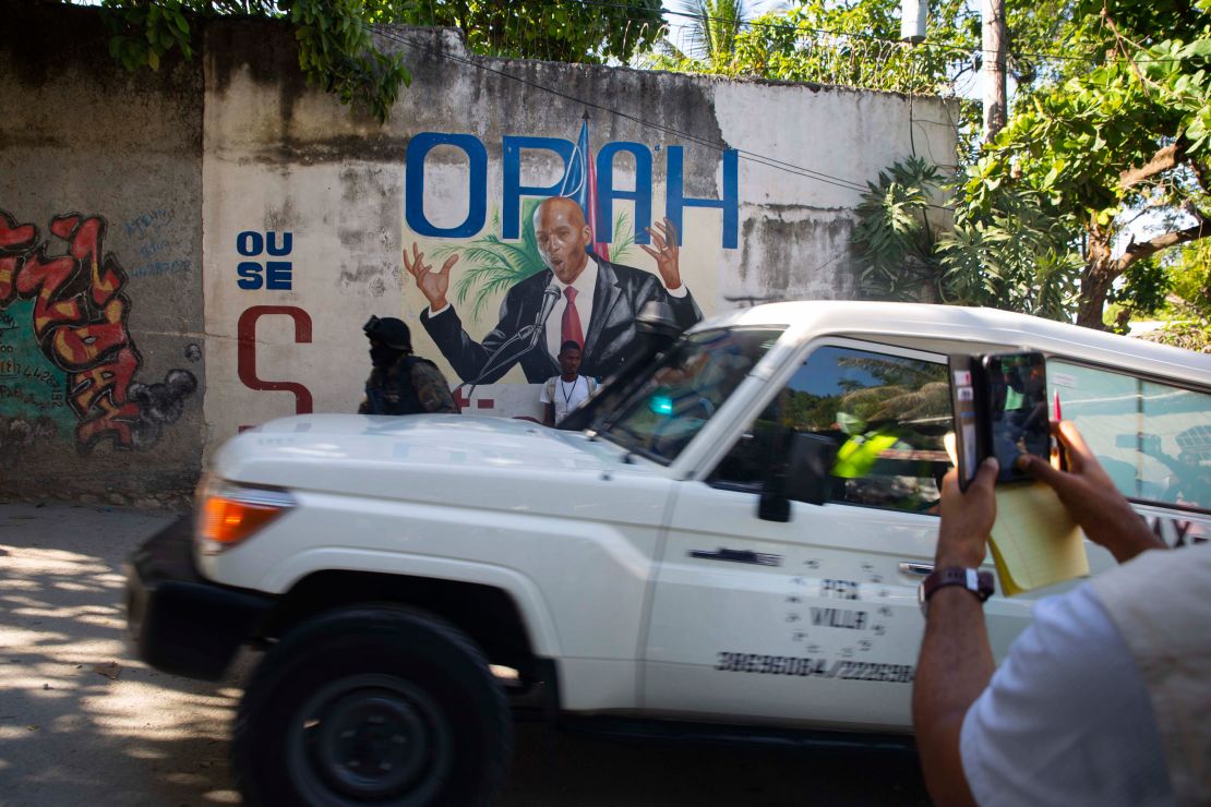 An ambulance carrying the body of Haiti's President Jovenel Moise drives past a mural featuring him near the leader's residence in Port-au-Prince, Haiti, on July 7.