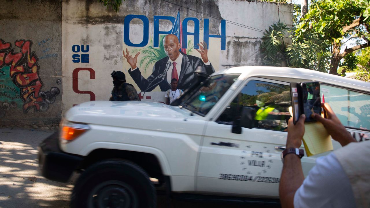 An ambulance carrying the body of Haiti's President Jovenel Moise drives past a mural featuring him near the leader's residence in Port-au-Prince, Haiti, on July 7.