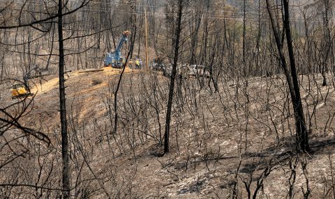 A utility crew works on power lines in front of a hillside that was burned by the Salt Fire in California's Shasta County.