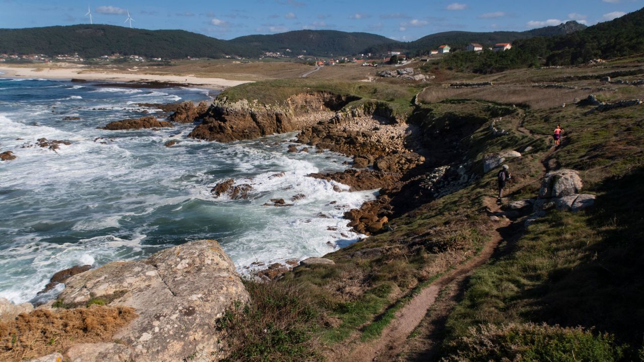 Hikers follow the lighthouse trail, Camiño dos Faros, near Traba Beach and the town of Laxe.