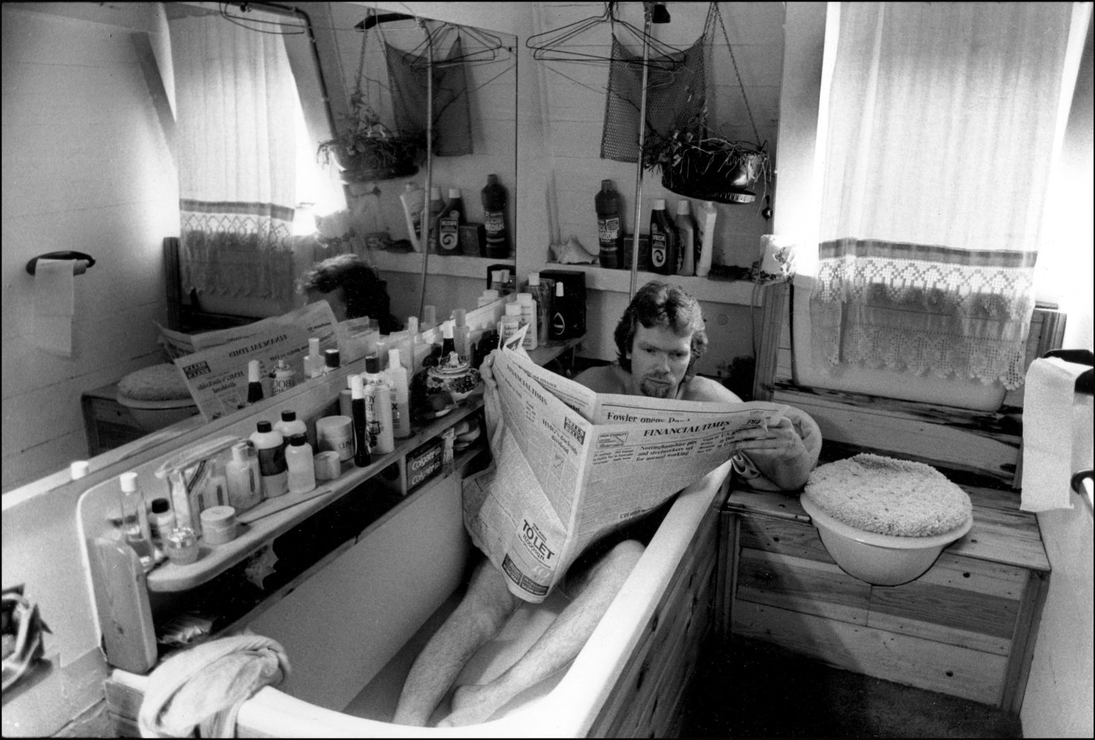 Branson reads the newspaper in a bathtub aboard his houseboat in London in 1984.