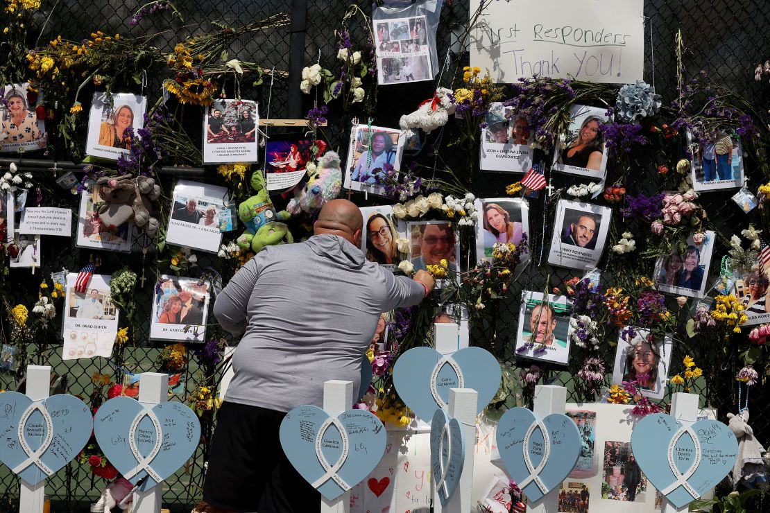 A man places flowers at the memorial that includes pictures of some of the victims.