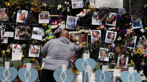 A man places flowers at the memorial that includes pictures of some of the victims.