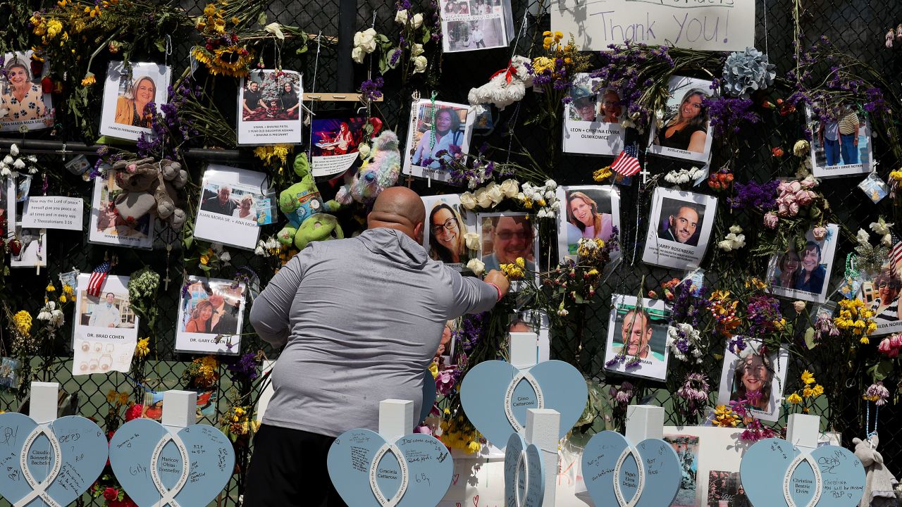A man places flowers in the memorial that includes pictures of some of the victims of the collapsed Champlain Towers South condo building on July 8.