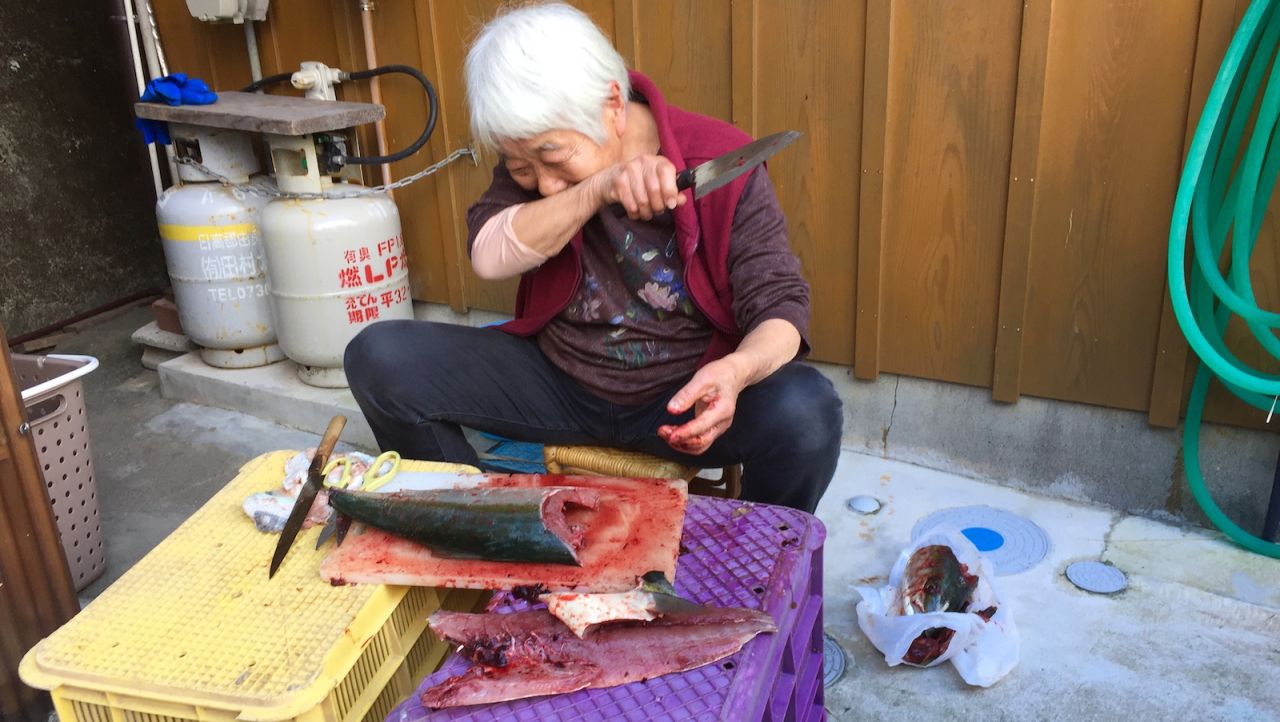 The writer's neighbor guts a fish outside her Ena home.