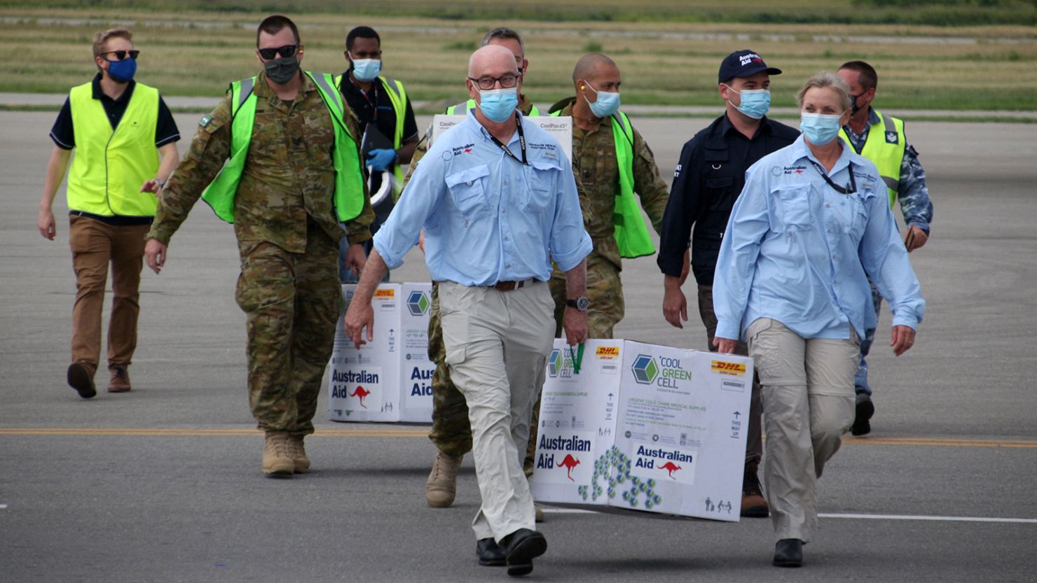 Australian officials carry boxes containing some 8,000 doses of the AstraZeneca vaccine at the Port Moresby international airport on March 23, 2021.