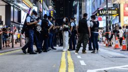 This picture taken in Hong Kong on July 2, 2021, shows police checking the belongings of a woman (C) holding flowers within a cordoned zone in the shopping district of Causeway Bay, near the site where a man stabbed a police officer in the back the night before, before stabbing himself in the chest and later dying of his wounds. - A 50-year-old man who died after stabbing a Hong Kong police officer was a "lone wolf" attacker who had been politically "radicalised", the city's security chief said on July 2. (Photo by Anthony WALLACE / AFP) (Photo by ANTHONY WALLACE/AFP via Getty Images)