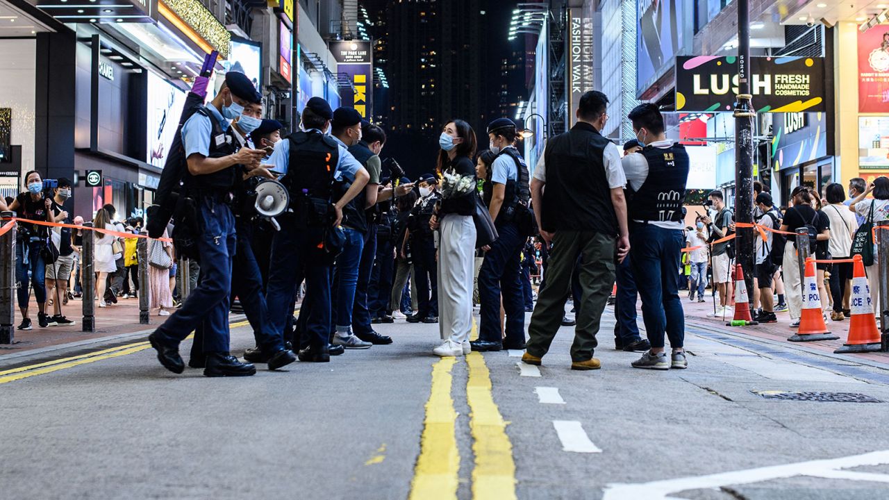 A woman holding flowers on July 2, 2021, in Causeway Bay, Hong Kong, near the site where a man stabbed a police officer in the back the night before.