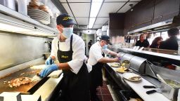 In this photo taken on June 15, 2021 kitchen staff continue wearing facemasks while preparing breakfast at Langer's Delicatessen-Restaurant in Los Angeles, California, on California's first day of fully reopening its economy after some fifteen months of Coronavirus pandemic restrictions.