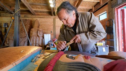 Lummi Nation lead carver Jewell James works on the final details of a nearly 25-foot totem pole to be gifted to the Biden administration at the end of July.