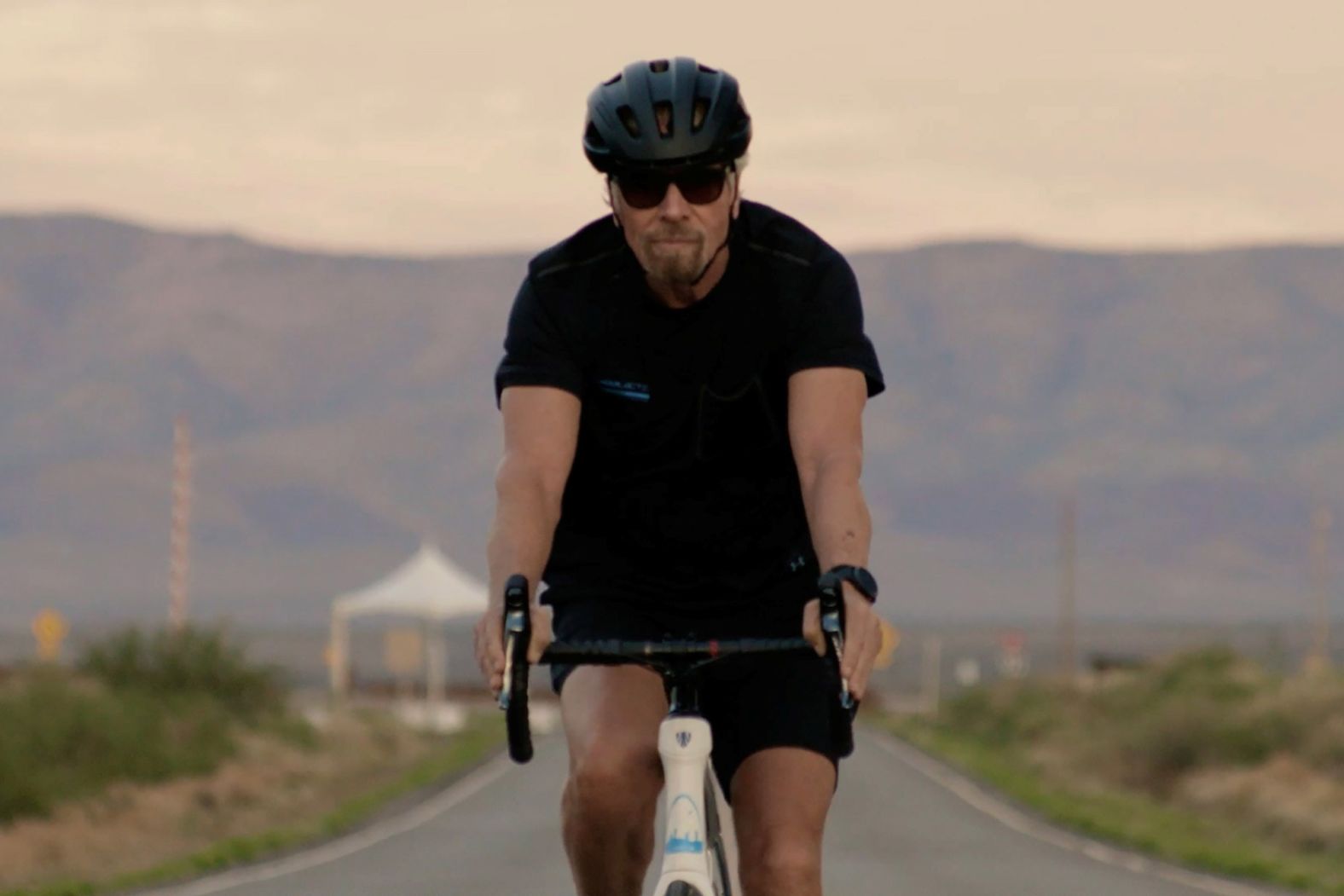 Branson arrives at Spaceport America by bicycle just after sunrise.