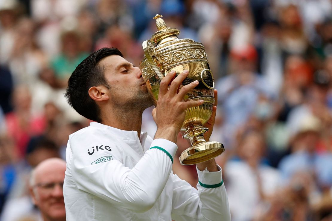 Novak Djokovic kisses the winner's trophy after beating Italy's Matteo Berrettini during their men's singles final match at the 2021 Wimbledon Championships.