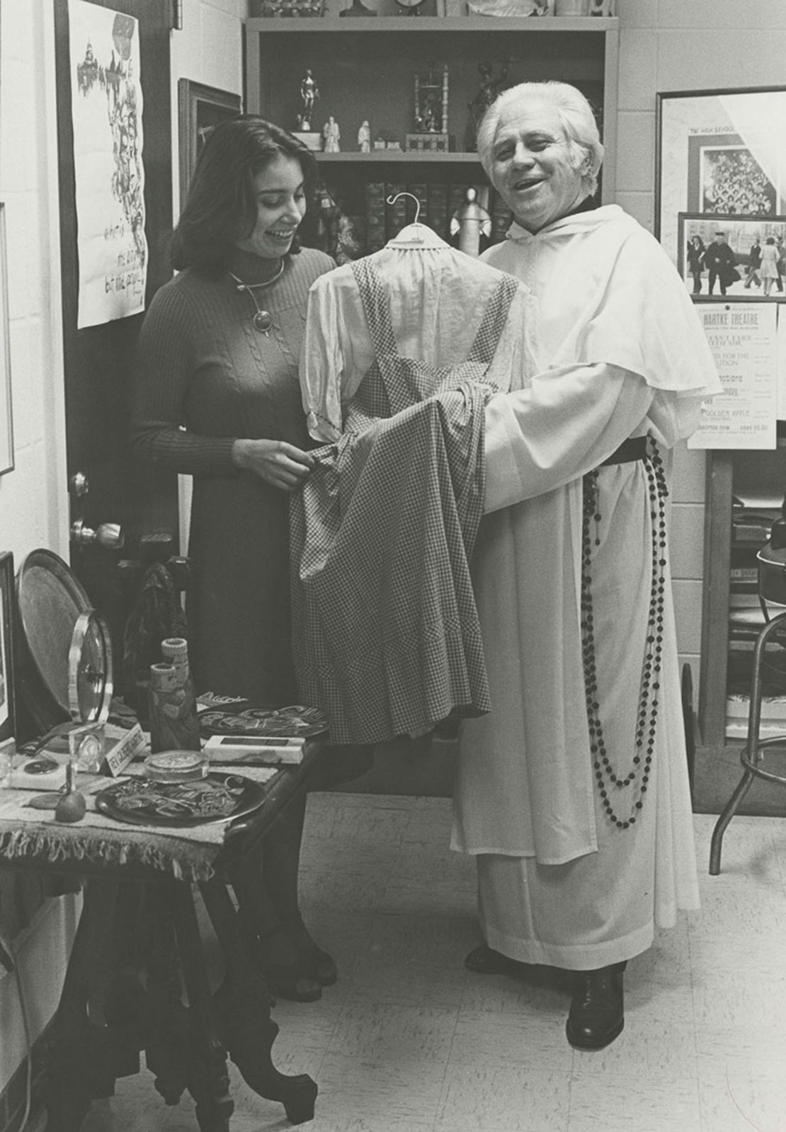An archive photo of Rev. Gilbert Hartke holding the dress. 