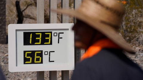 People visit a thermometer Sunday in Death Valley National Park.