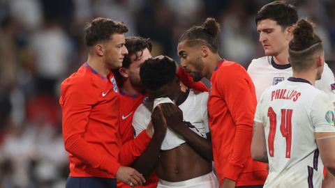 England players comfort teammate Saka after he missed a penalty during a penalty shootout after extra time against Italy.