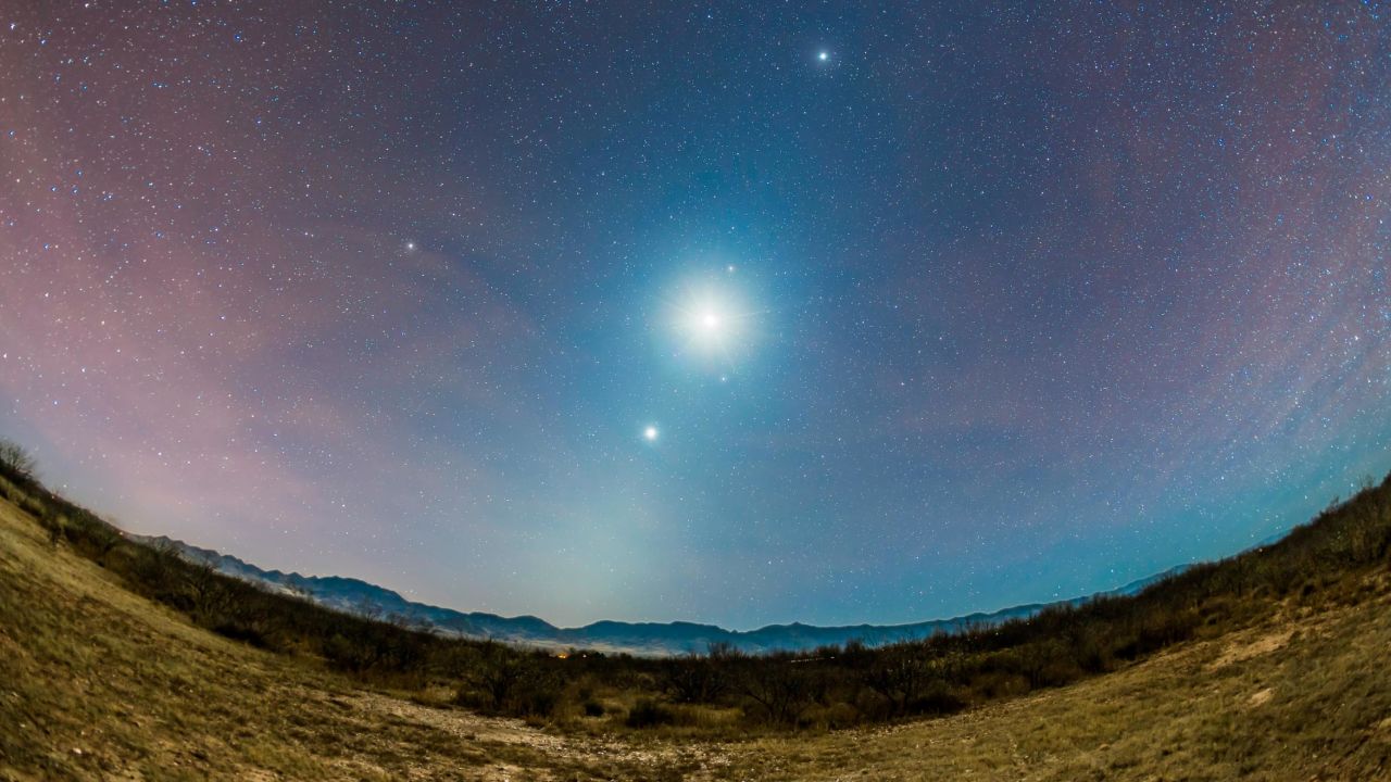 The brightest object in the night sky, the moon is shown flanked by three planets: Venus (below); Mars, just above the moon; and Jupiter (top), as seen in Portal, Arizona, December 6, 2015.
