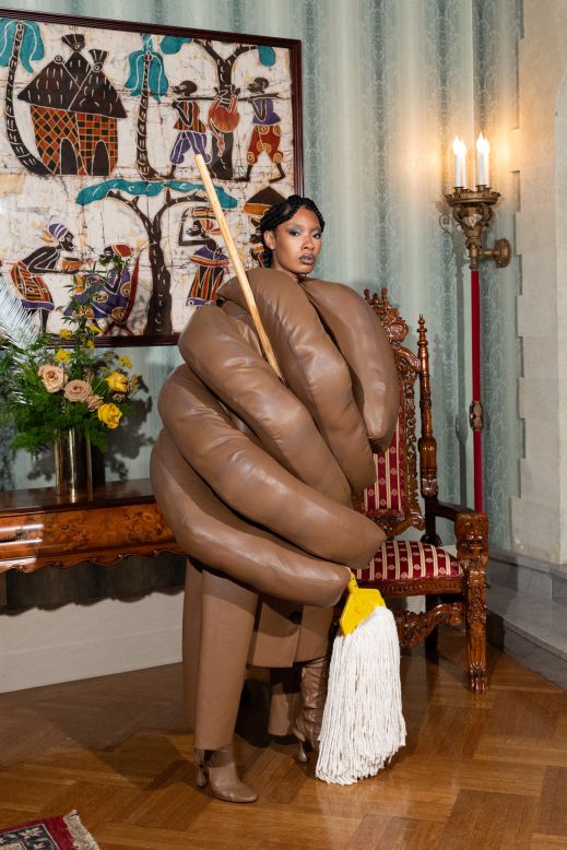 A sculptural outfit resembling a hand holding a mop. 