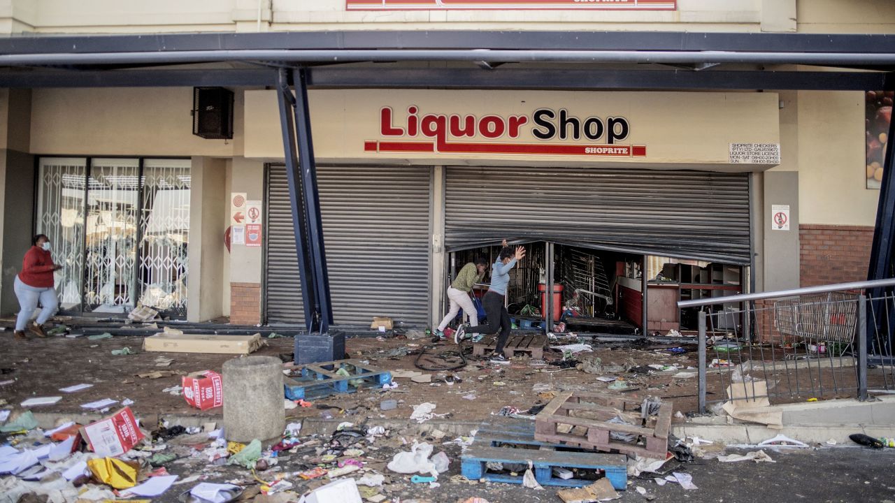 Rioters run from police officers after looting a liquor shop at the Jabulani Mall in the Soweto district of Johannesburg on Monday.