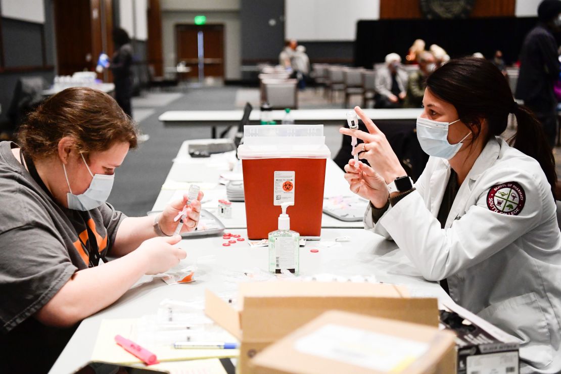 Marissa Dixon, left, an employee at University of Tennessee's student health center, and Mateasha Edwards of South College draw coronavirus vaccines in the student union at the University of Tennessee on February 12, 2021.