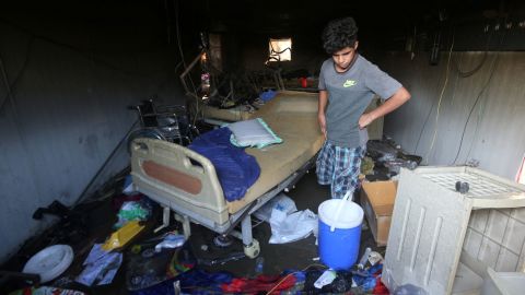 A man stands next to a hospital bed as he examines the damage following the blaze at the coronavirus facility.