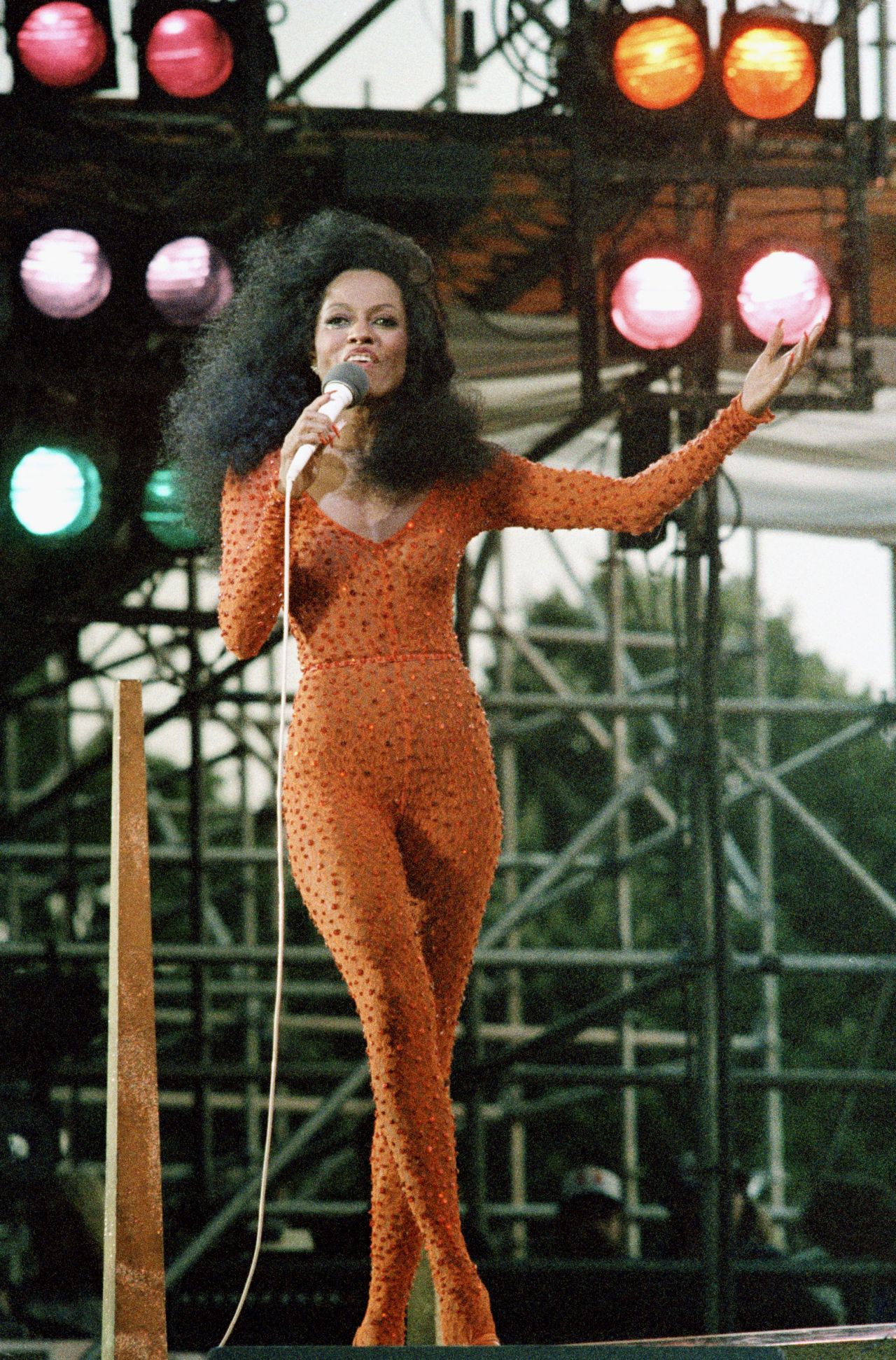 Diana Ross wears an orange jumpsuit as she performs in Central Park at the televised 1983 concert. 