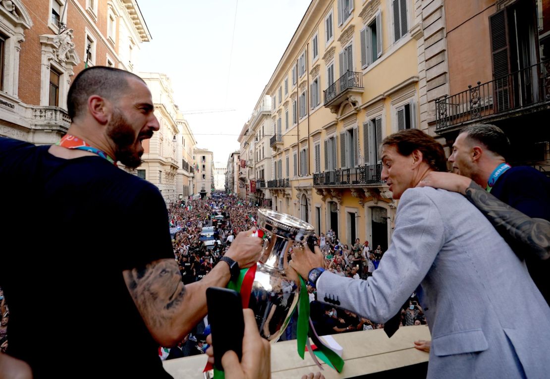 Leonardo Bonucci and Roberto Mancini celebrate during national team's open-top bus parade in Rome.