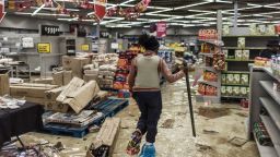 A South Africa police officer inspects the damages at a looted mall in Vosloorus, on July 13, 2021. - Stores in two South African provinces were ransacked for a fifth consecutive day, hours after President Cyril Ramaphosa deployed troops in a bid to quell unrest that has claimed 45 lives. The premier of Gauteng province, which includes Johannesburg, said 10 bodies were found late on July 12 at a looted shopping centre in Soweto, on the city's outskirts. (Photo by MARCO LONGARI / AFP) (Photo by MARCO LONGARI/AFP via Getty Images)
