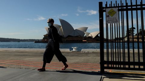 A pedestrian wearing a face mask walks past the Sydney Opera House in Sydney on July 13, 2021. The city is currently in lockdown to curb a fast-growing coronavirus outbreak.  