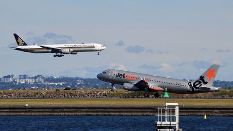 A Singapore AirLines (L) aircraft lands next to a Jet star aircraft taking flight at Sydney International Airport on June 4, 2021, as the Australian Bureau of Statistics reported the country's economy in the year's first quarter has rebounded to pre-pandemic levels. (Photo by Saeed KHAN / AFP) (Photo by SAEED KHAN/AFP via Getty Images)