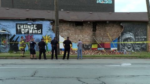 Police and firefighters stand near the George Floyd mural after it collapsed on Tuesday.