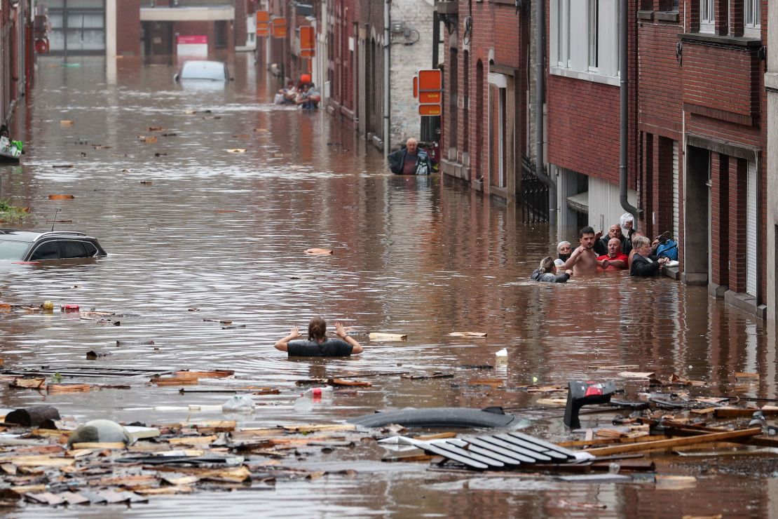 A woman tries to move in a flooded street following heavy rains in Liege, Belgium.