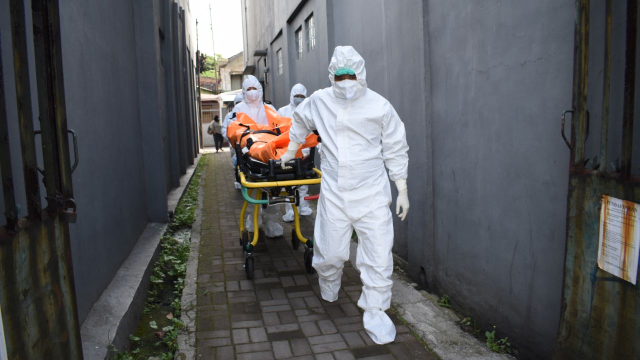 Health workers remove the body of a Covid-19 victim who died while isolating at home in Indonesia on Wednesday.