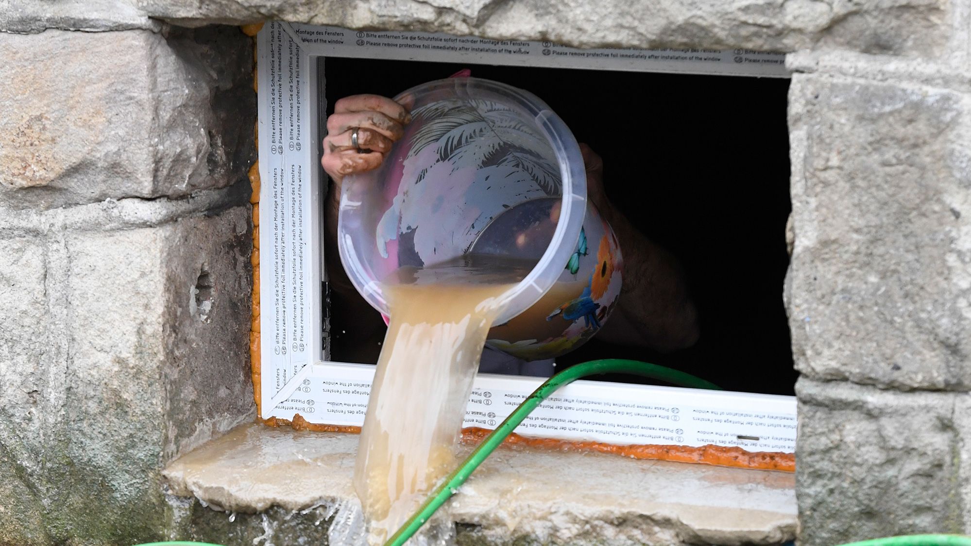 A resident uses a bucket to remove water from a house cellar in Hagen, Germany.