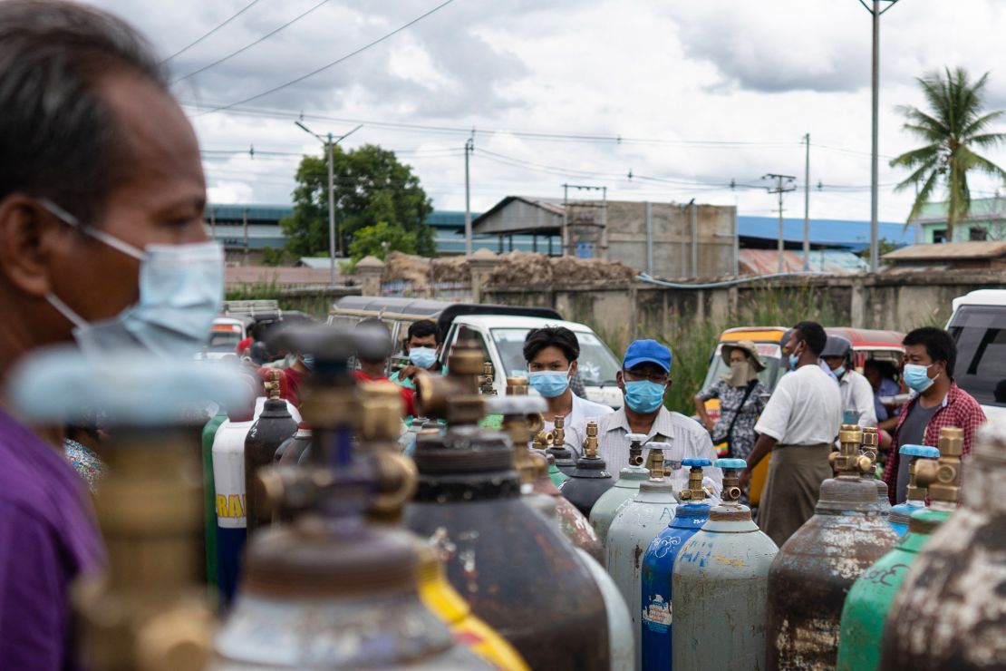 People wait to fill up empty oxygen canisters outside a factory in Mandalay on July 13.