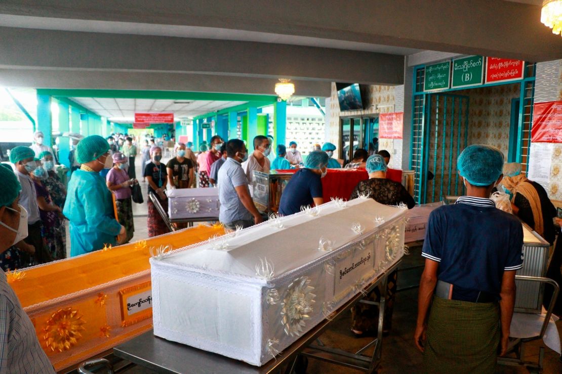 People wearing face masks wait while caskets with bodies are queued outside a crematorium at the Yay Way cemetery in Yangon, Myanmar, on July 14.