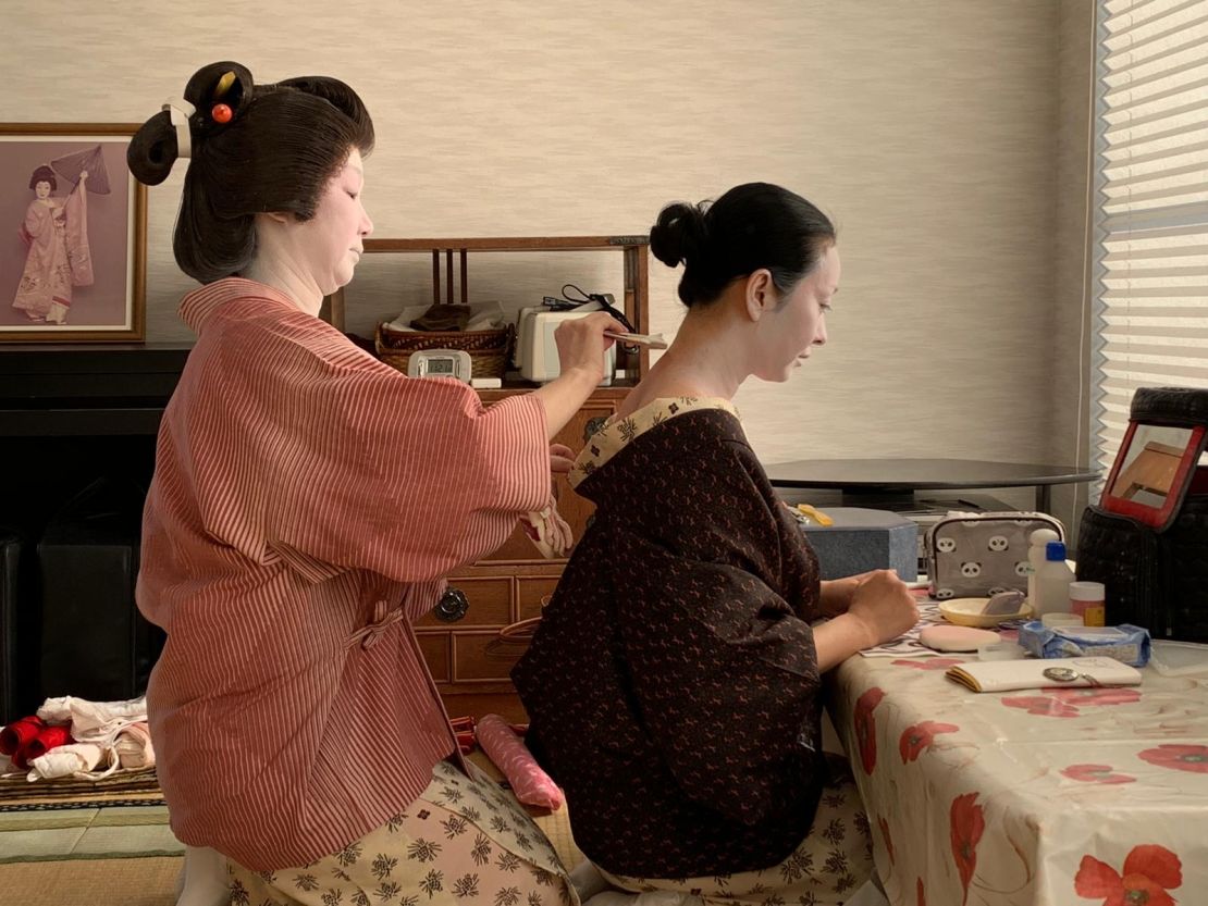 Geishas behind-the-scenes applying their traditional makeup. 