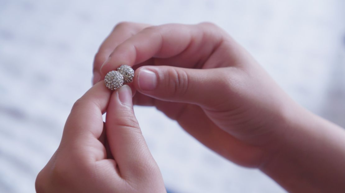 Montserrat holds up her mom's earrings. They were the last thing her mother gave her before they were separated.