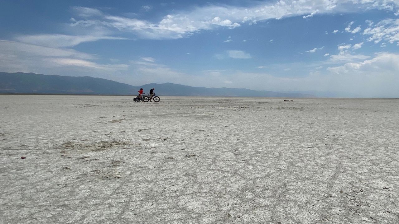 Lucy Kafanov of CNN and Kevin Perry ride bikes Tuesday on the dry lake bed playa of the Great Salt Lake.