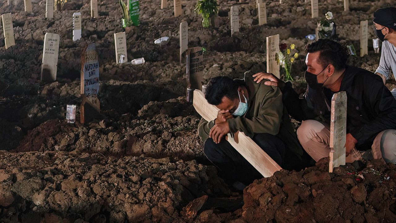 Relatives wearing face masks mourn a coronavirus victim at Rorotan public cemetery in Jakarta.
