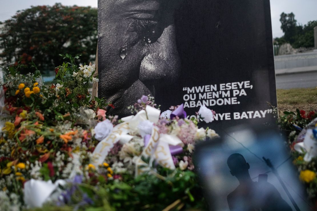 A man is reflected on a cellphone at a memorial outside the Presidential Palace in memory of slain President Jovenel Moise, in Port-au-Prince, Haiti, Wednesday, July 14, 2021.