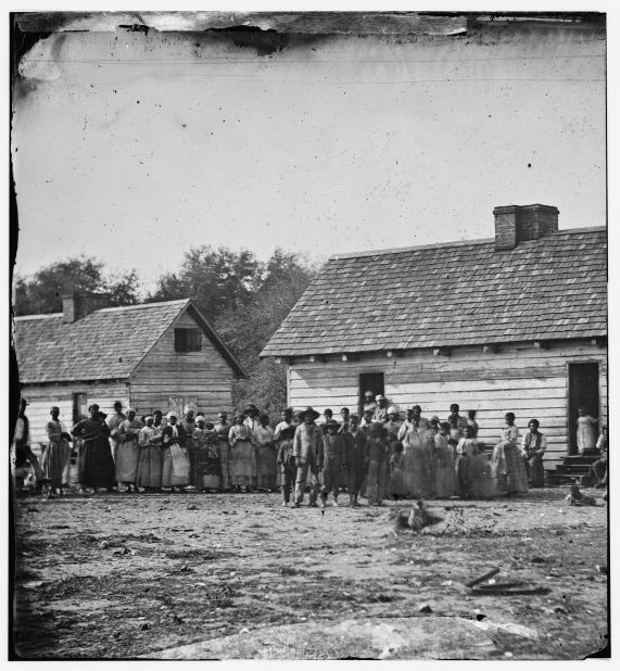 Enslaved men, women and children photographed standing in front of buildings on Smith's Plantation, Beaufort, South Carolina. 