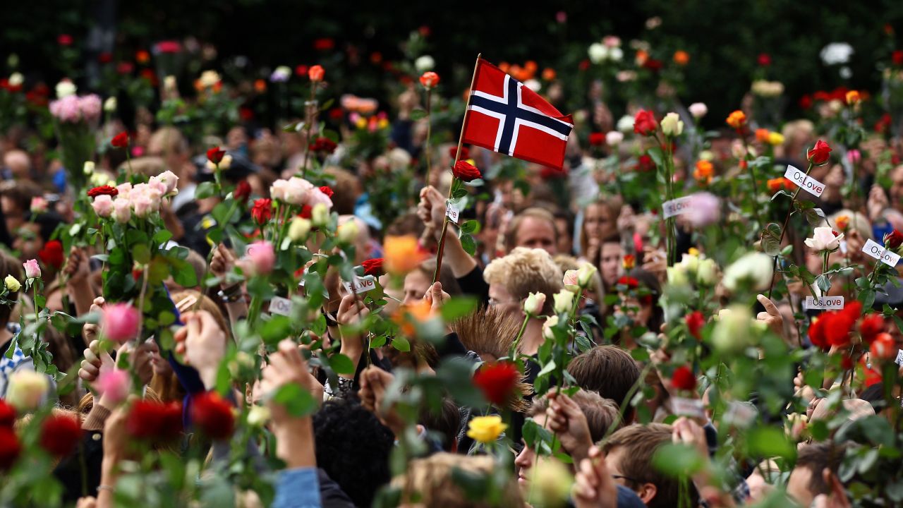 A Norwegian flag and dozens of flowers are held up as tens of thousands of people gather in Oslo city center for a vigil on July 25, 2011, three days after the attacks.