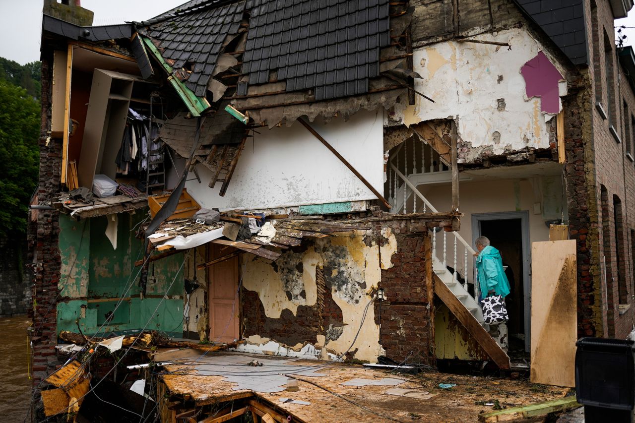 A woman walks up the stairs of her damaged house in Ensival, Belgium.