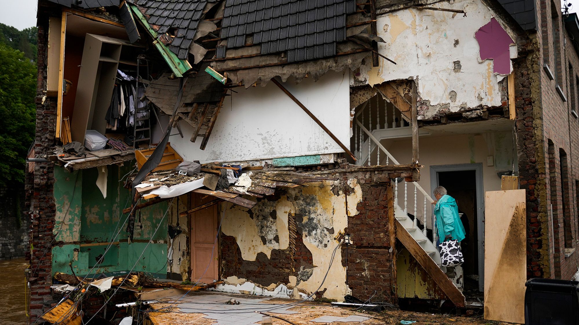 A woman walks up the stairs of her damaged house in Ensival, Belgium.