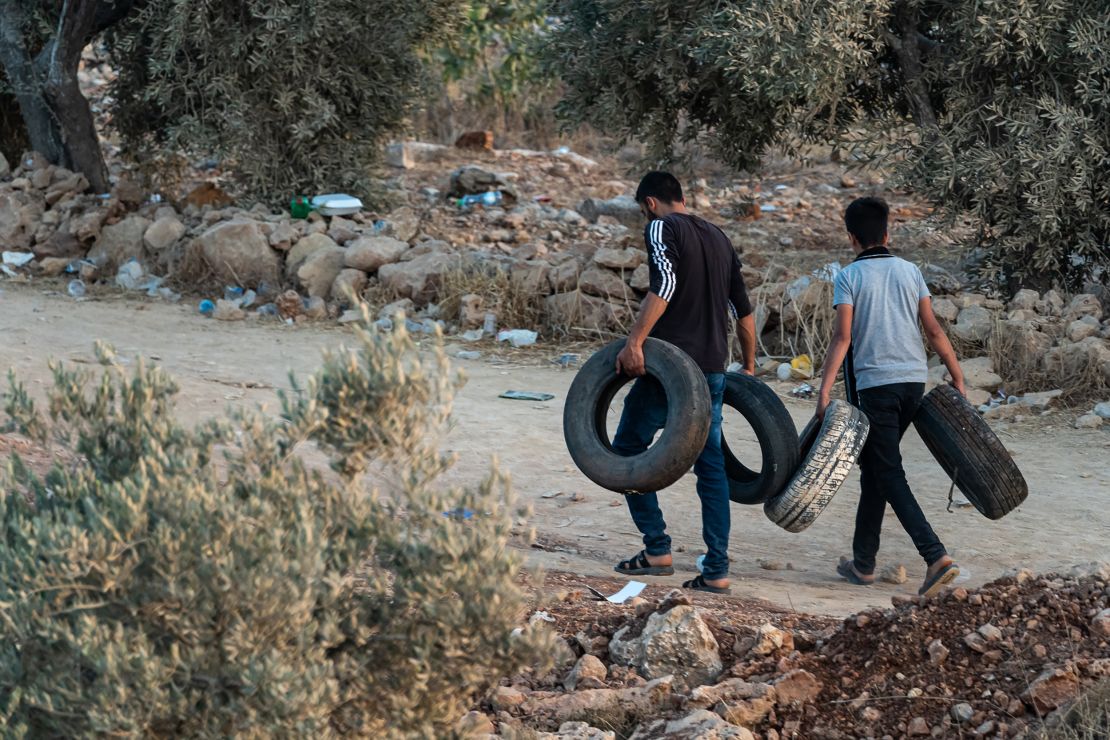 Young Palestinian men carrying tires ready to set them alight, in Beita, West Bank, on July 2.