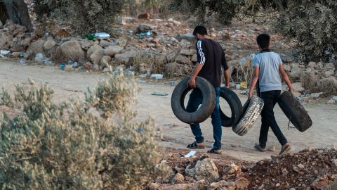 Young Palestinian men carrying tires ready to set them alight, in Beita, West Bank, on July 2.