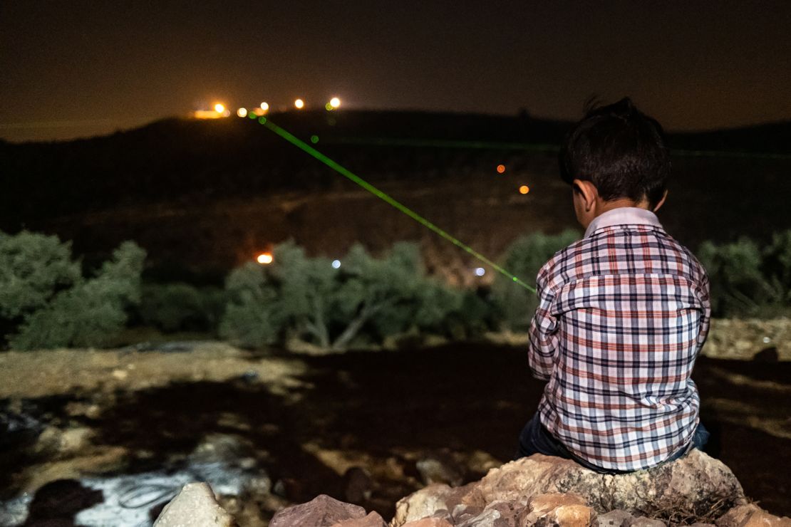 A Palestinian boy shines a green laser at the illegal settlement of Givat Evyatar, West Bank, on July 2.